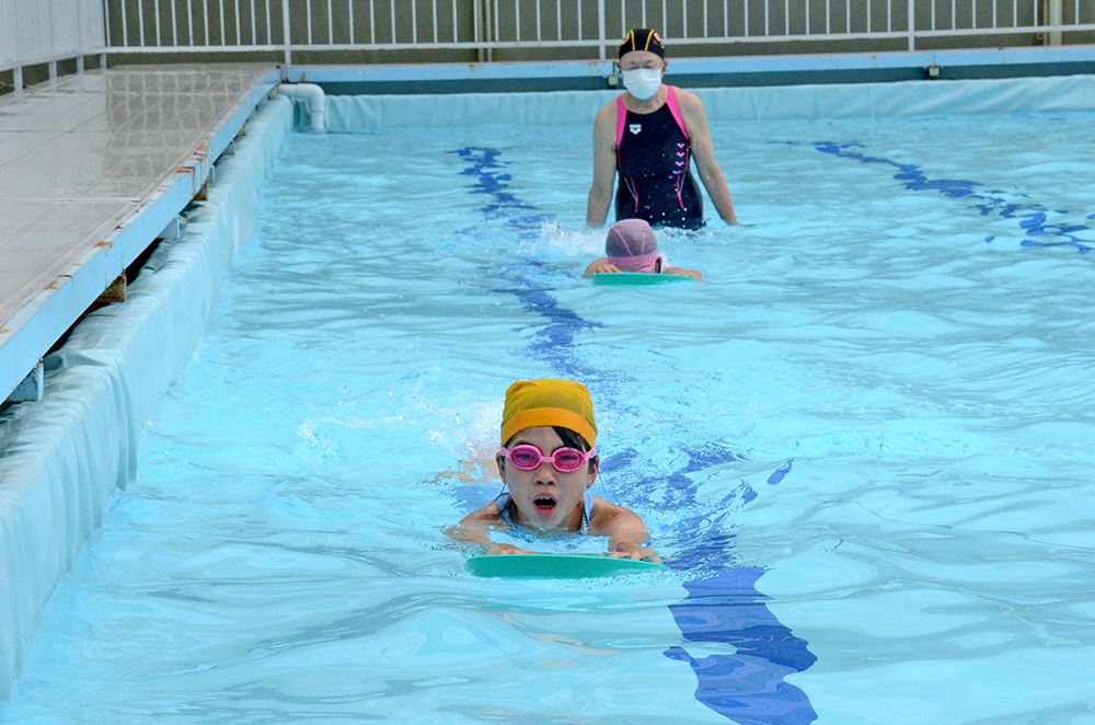 ビート板を使って泳ぐ練習をする児童たち