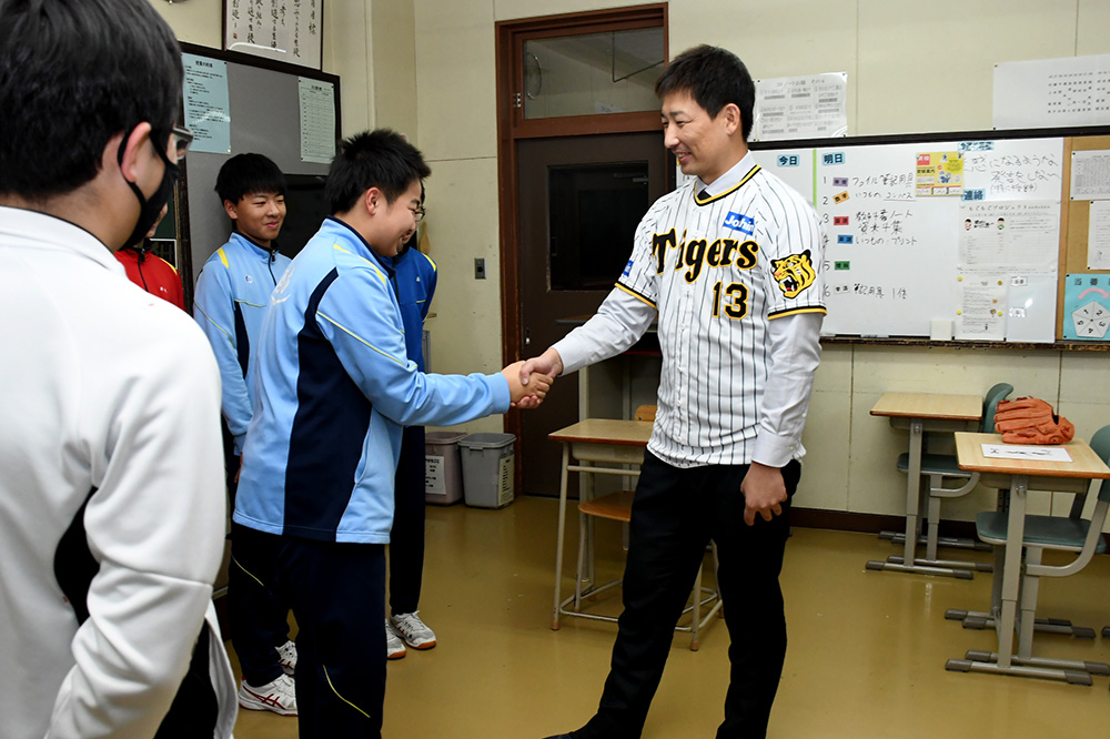 南中学校野球部の選手と握手をする岩崎優投手